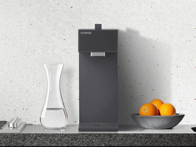 현대적인 주방 인테리어에 배치된 코웨이 스위치 직수정수기 P-2201N 차콜 블랙 모델의 슬림한 디자인